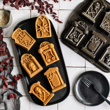 Tombstone cakelets on black plate with Pan, white tile backdrop