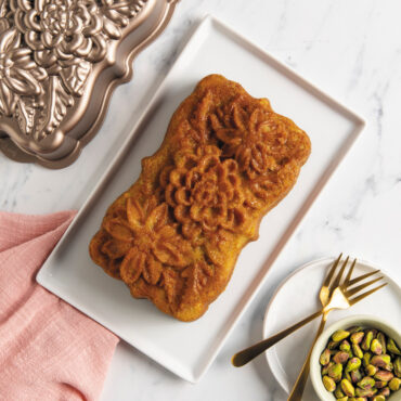 Plain Wildflower loaf cake on rectangular plate with pan and pasticcios in a small dish