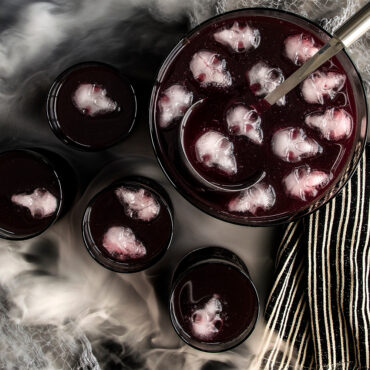 Six golden skull-shaped cakelets with detailed bone decorations baked in Nordic Ware aluminum Skull Bites pan