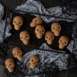 Baked mini skull cakes on platter with black sugar, Halloween props