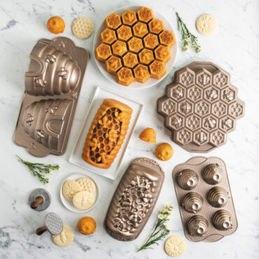 group shot of honey hive loaf pan, honey bee cookie stamps, beehive cakelet pan, honeycomb pull apart pan, beehive cake pan, and busy bee bitelet pan