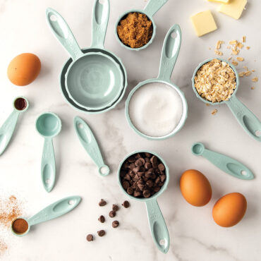 Nordic Ware sea glass colored measuring cups and spoons arranged with baking ingredients overhead view