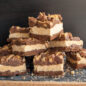 Baked peanut butter layer bars on surface, cut pieces stacked.