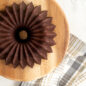 Baked chocolate Brilliance 5 Cup Bundt on wooden platter with towel.