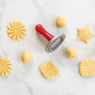 Stamped dough on surface using Pretty Pleated Cookie Stamps, 3 designs shown with dough balls