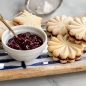 Stamped cookie sandwiches filled with berry jam, dusted with powdered sugar