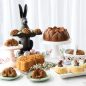Easter baking display with baked bunny cakes, baked baskets, Bundt cake and floral loaf cake.