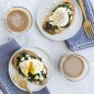 Poached eggs with spinach, feta cheese on toast on plate, cups of coffee