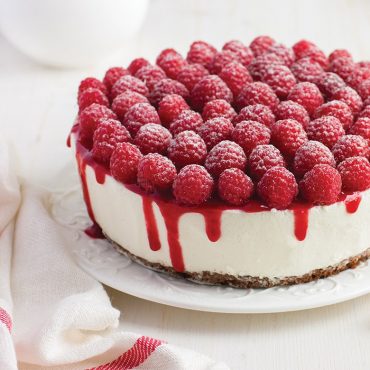 Baked cheesecake topped with fresh raspberries and glaze on plate