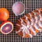 Baked blood orange Jubilee loaf cake with blood orange glaze, cut blood orange and whole orange on cooling rack, glaze pitcher