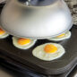 Stovetop cooking eggs on griddle with dome lid