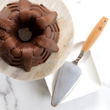 Overhead baked chocolate Marquee Bundt on cake stand with cake server on plate.