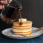 GIF maple syrup pouring on cooked stacked pancakes.