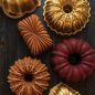 Group shot of baked Bundts and loaf cake with pans on surface