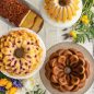 Top view of baked Lotus Bundt, Wildflower Loaf, Magnolia Bundt, Blossom Bundt cakes on serving plates with flowers