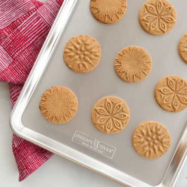 Baked gingerbread cookies with stamped star and moon designs on Nordic Ware half sheet pan