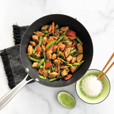 nordic ware spun 10 inch medium sized wok with silver handle filled with mixed veggies and chicken