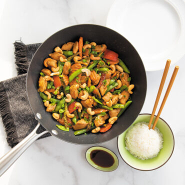 nordic ware spun 10 inch medium sized wok with silver handle filled with mixed veggies and chicken