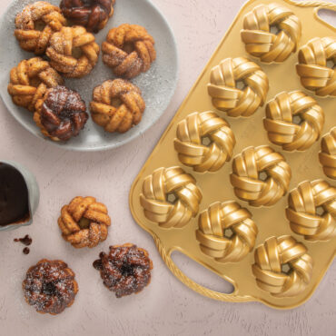 Cast aluminum mini bundt pan with braided design pattern, displaying golden baked mini bundt cakes