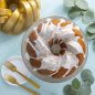 75th Anniversary Braided Bundt® Baked Cake with glaze, pan and plate on background