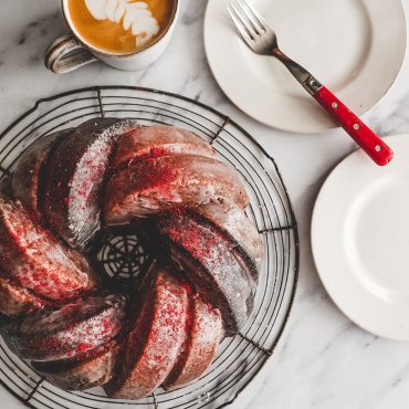 Neapolitan Bundt Cake Glazed on cooling rack with plates and latte
