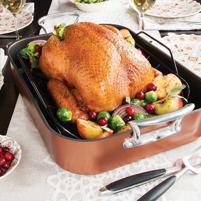 Image of a roasted turkey in Nordic Ware's ceramic copper roaster in a Thanksgiving table scene.
