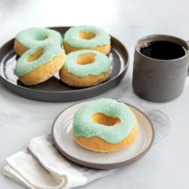 Baked donutes with teal frosting and cup of coffee