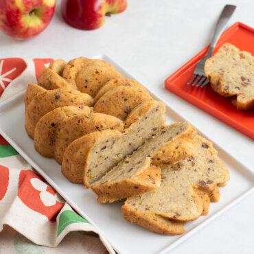 sliced apple zucchini loaf on a white plate baked in nordic ware braided loaf pan with twisted rope design