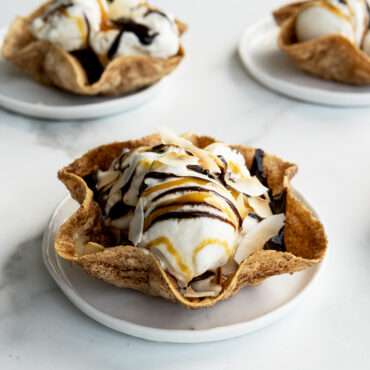 Side angle of baked tortilla ice cream bowls filled with ice cream and chocolate sauce