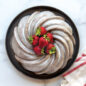 Baked swirled bundt cake with white glaze topped with strawberries