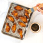 Brushing marinade on chicken wings on cooling grid