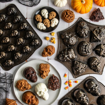 Group image of Monster Mask Cakelets, Skull Cakelets, and Skull bites with pans on white tile backdrop