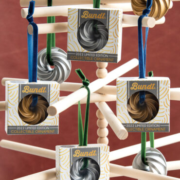 silver and gold aluminum Heritage Bundt ornaments displayed in open box beside decorated miniature Christmas tree
