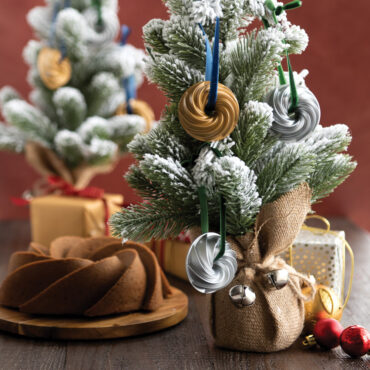 Two gold-colored Nordic Ware Heritage Bundt pan ornaments with detailed fluted ridges, miniature collectible versions