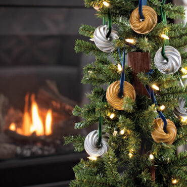 Two miniature Nordic Ware Heritage Bundt pan ornaments in gold and silver finishes hanging on decorated Christmas tree