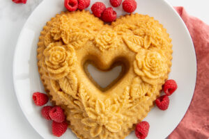 Baked floral heart bundt on plate with raspberries