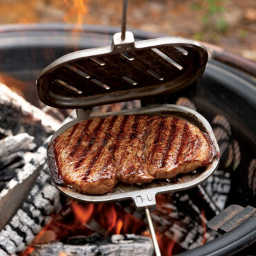 Campfire griller open with steak on open fire