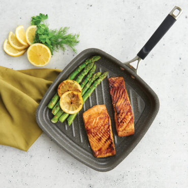 A overhead image of the searing grill pan with salmon, vegetables, and lemon cooked and ready to serve.