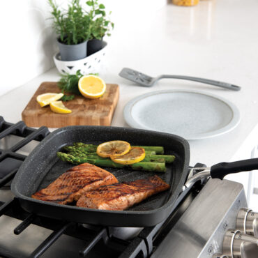 A side image of the searing grill pan on the stovetop cooking salmon with vegetables