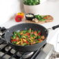 Side image of the Wok on the stovetop cooking stir fry with fresh vegetables.