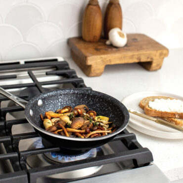 A beauty image of the 8" Saute Skillet on the stovetop cooking a variety of delicious mushrooms.