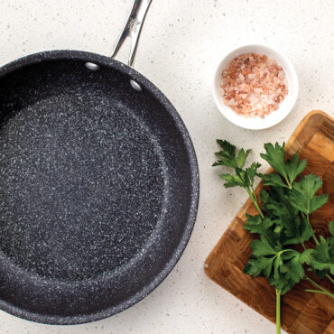 An overhead image of the 10" saute skillet empty with a side of cilantro and salt for food prepping.