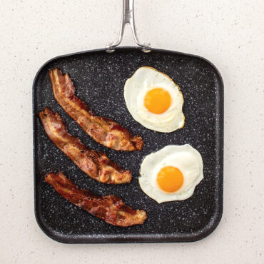 a overhead image of the 11" square griddle with bacon and eggs cooking on the griddle.