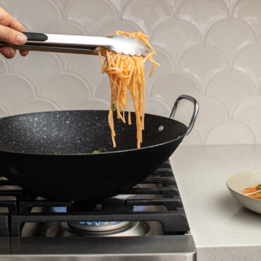A visually appealing image showcasing a 14-inch wok in action. The wok, with its sleek design and nonstick surface, is perfect for stir-frying a variety of ingredients. Explore the joy of cooking with this versatile and high-quality wok.