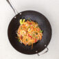An appetizing image showcasing a 14-inch wok filled with delicious noodles. The wok, featuring a speckle pattern and a nonstick surface, is perfect for stir-frying and creating mouthwatering Asian-inspired dishes.
