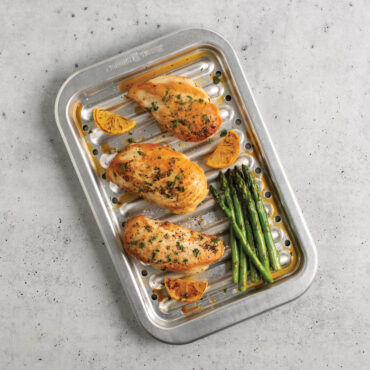 chicken and veggies on Nordic Ware natural aluminum broiler pan with slotted rack, roasted vegetables and meat visible