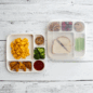 GIF- Overhead of image of divided plates with a kids meals with lid moving from one plate to the other