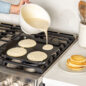 Pouring pancake batter with better batter bowl onto a griddle on stovetop