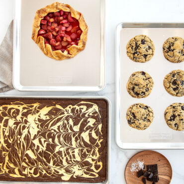 3 sheet pans filled with baked goods such as a berry galette, chocolate chip cookies and brownie bars.