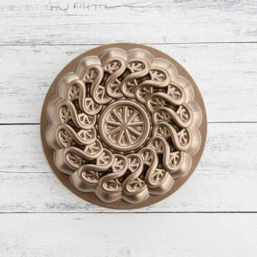 Image of Citrus Twist Cake Pan on a white wood background showing up-close details of the citrus fruits sliced and twisted on the pan creating a beautiful pattern.